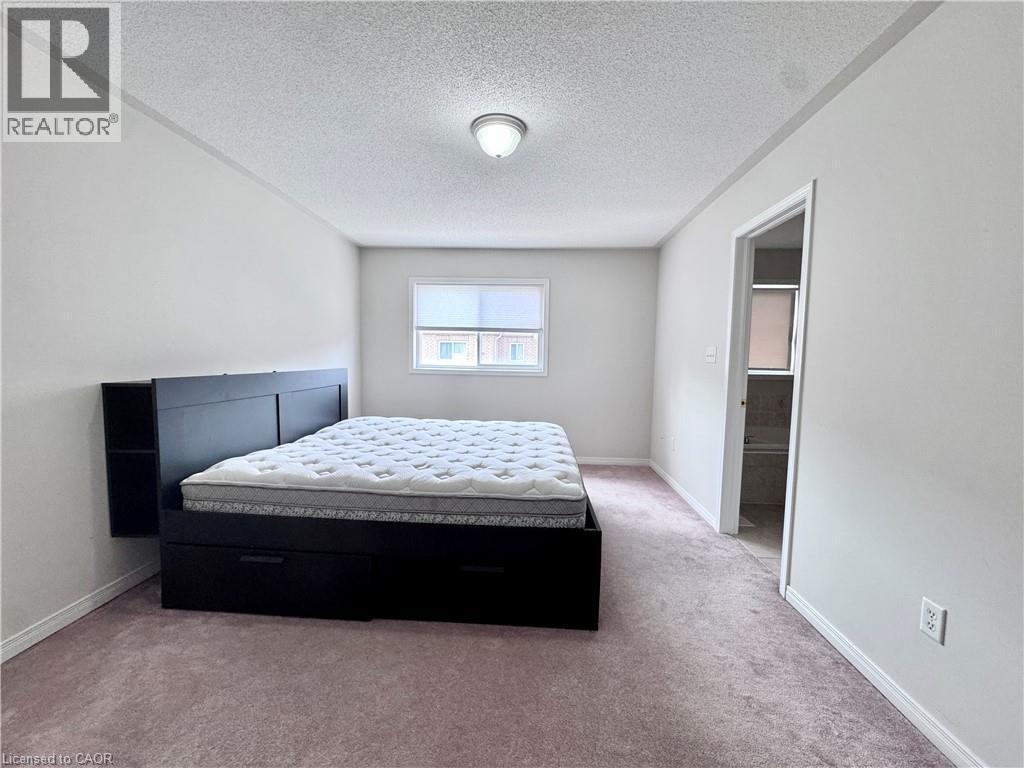 Carpeted room featuring a ceiling-mounted light fixture, a window with a blind, and a doorway opening to an additional space - 110 Highland Road E Unit# 53, Kitchener, ON - Indoor Photo Showing Bedroom