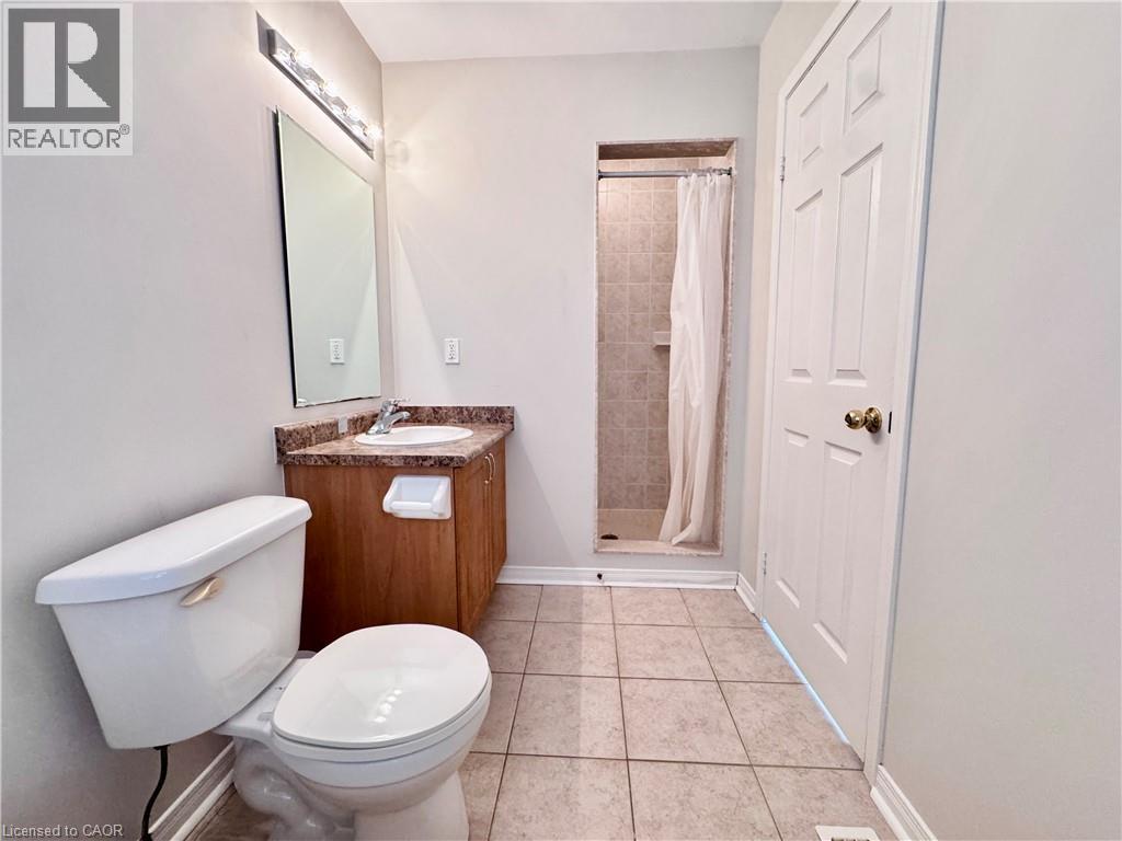 Bathroom featuring a vanity with a countertop sink, an overhead light fixture, a tiled shower, and ceramic tile flooring - 110 Highland Road E Unit# 53, Kitchener, ON - Indoor Photo Showing Bathroom