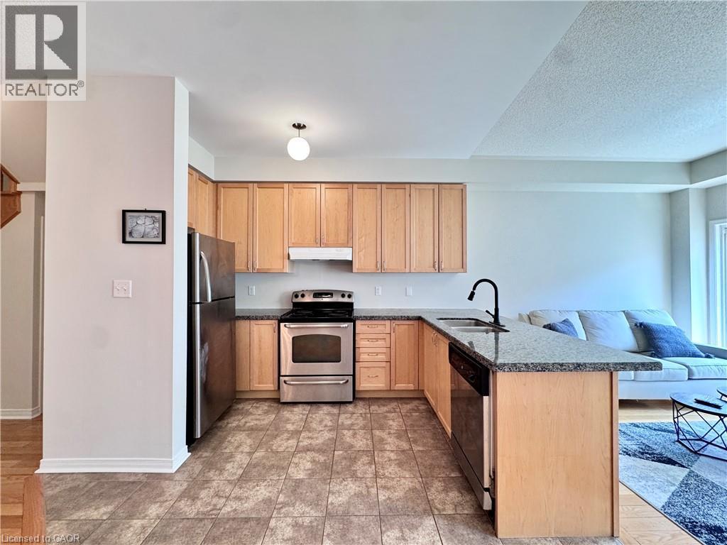 Open-concept kitchen featuring wood cabinetry, stainless steel appliances, granite-style countertops, and a U-shaped layout with a breakfast bar - 110 Highland Road E Unit# 53, Kitchener, ON - Indoor Photo Showing Kitchen