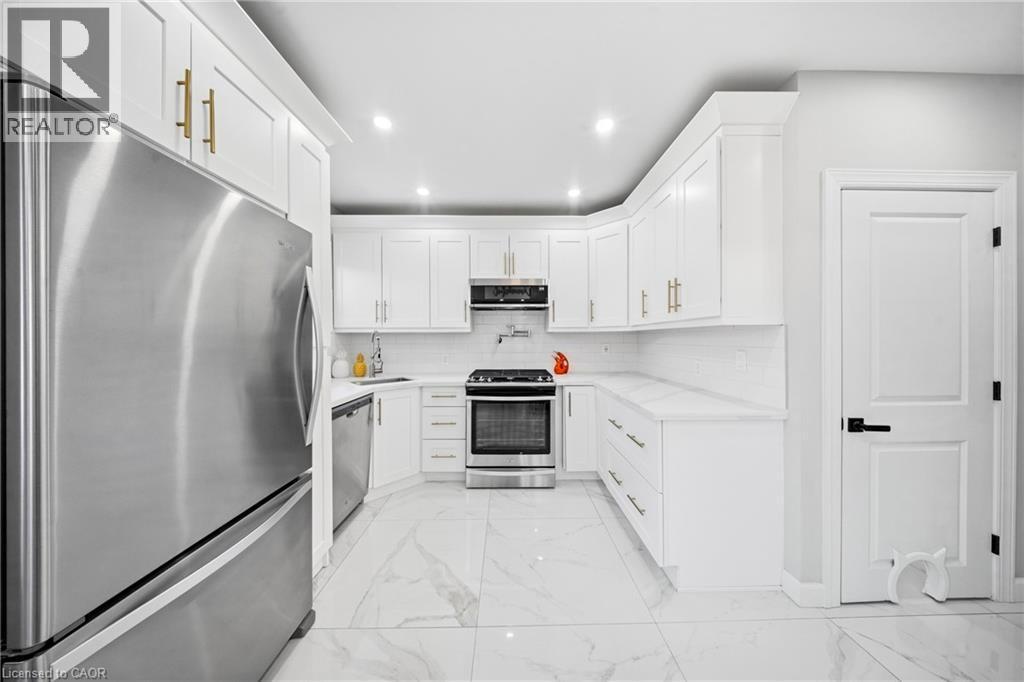 Kitchen with stainless steel appliances, light marble finish floors, white cabinets, recessed lighting, and light stone counters - 273 Stinson Crescent, Hamilton, ON - Indoor Photo Showing Kitchen