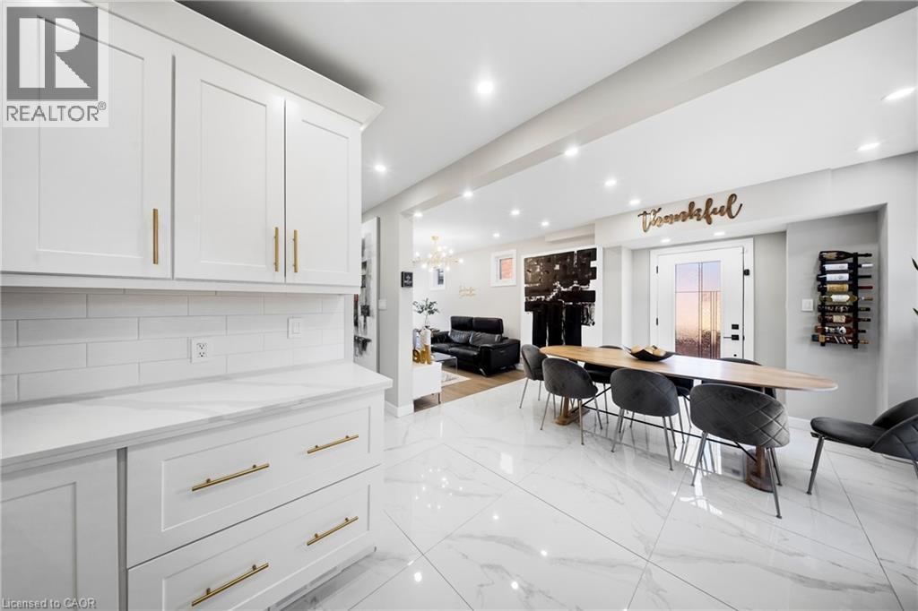 Kitchen featuring open floor plan, white cabinetry, light stone counters, backsplash, and light marble finish floors - 273 Stinson Crescent, Hamilton, ON - Indoor Photo Showing Other Room