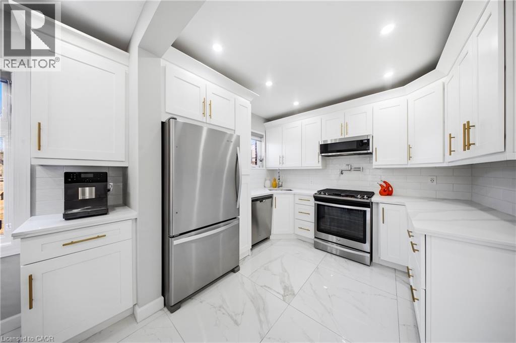 Kitchen featuring stainless steel appliances, light marble finish floors, white cabinetry, light stone countertops, and recessed lighting - 273 Stinson Crescent, Hamilton, ON - Indoor Photo Showing Kitchen
