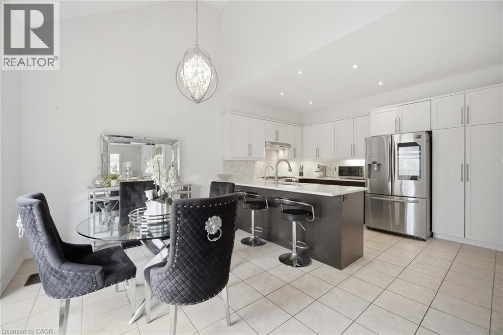 Open-concept kitchen and dining area featuring a vaulted ceiling and an ornate chandelier - 58 Doon Creek Street, Kitchener, ON - Indoor