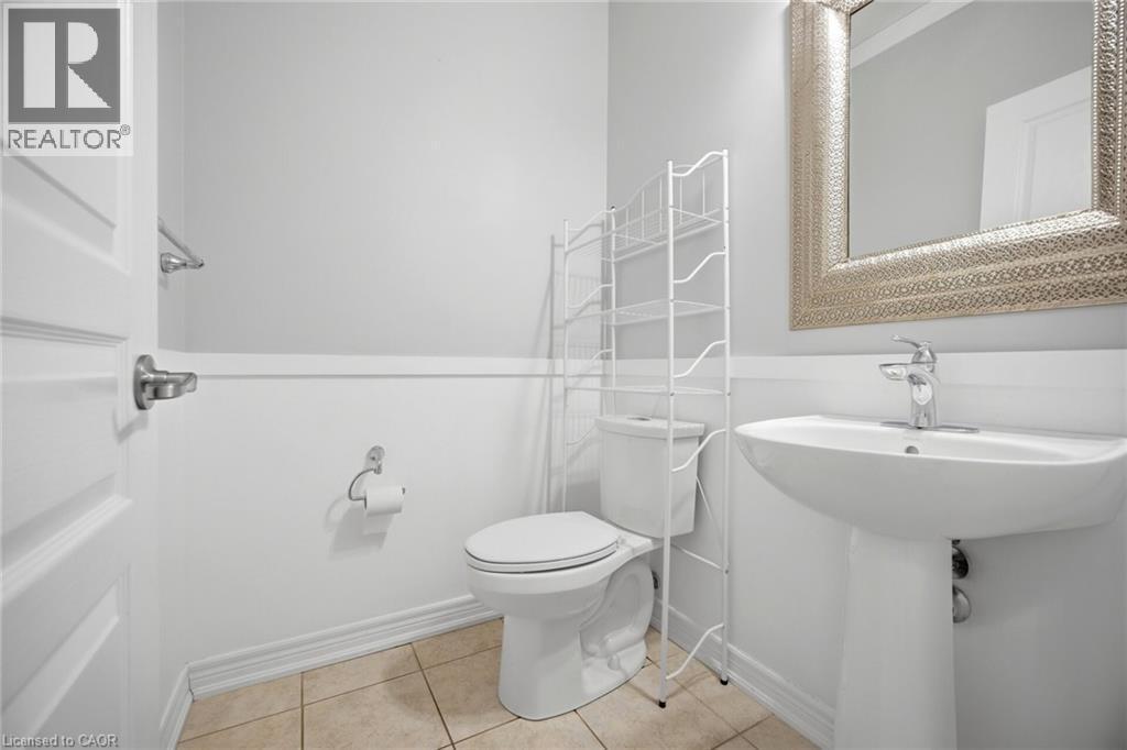 Pedestal sink with chrome faucet, complemented by a decorative framed mirror - 58 Doon Creek Street, Kitchener, ON - Indoor Photo Showing Bathroom