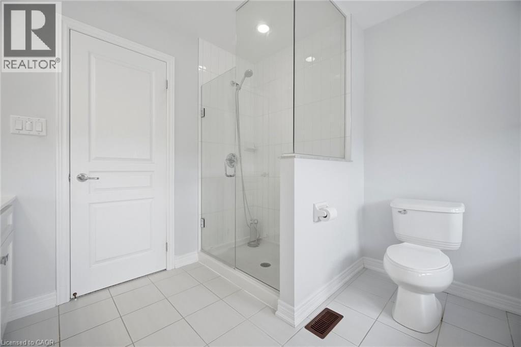 Bathroom featuring a glass-enclosed shower, white tile flooring, and a standard toilet - 58 Doon Creek Street, Kitchener, ON - Indoor Photo Showing Bathroom