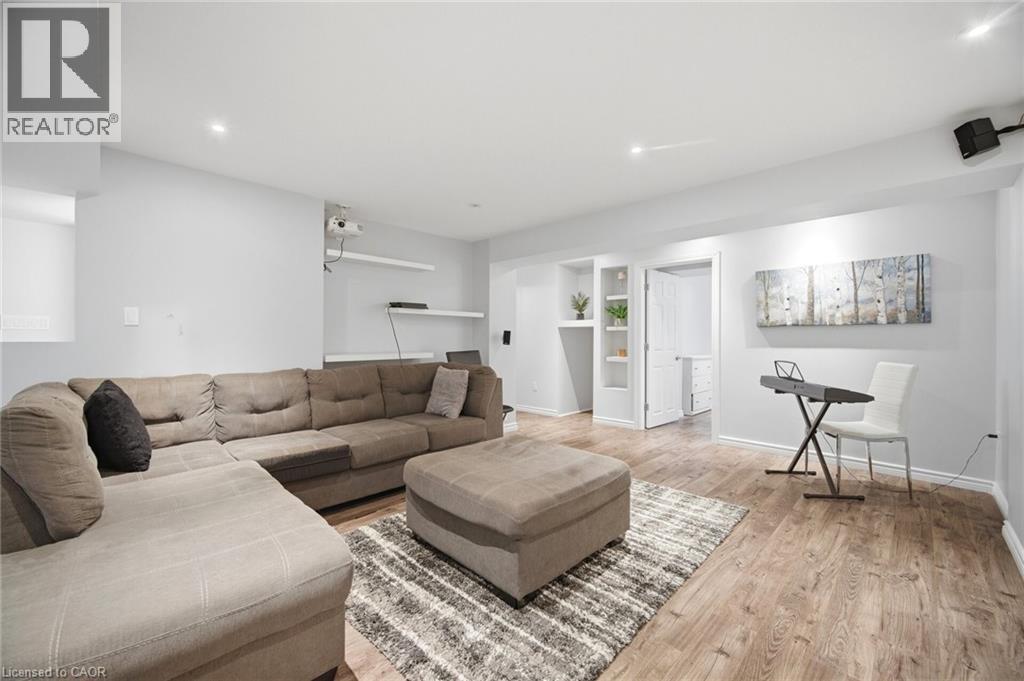 Spacious finished room featuring wood-finish flooring, recessed lighting, and built-in shelving - 58 Doon Creek Street, Kitchener, ON - Indoor Photo Showing Living Room