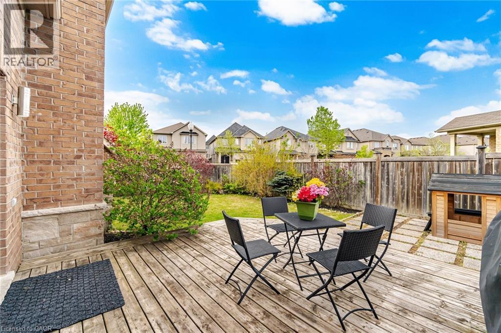 Expansive wooden deck with a privacy fence, stone patio pavers, manicured lawn, and mature perimeter landscaping - 58 Doon Creek Street, Kitchener, ON - Outdoor With Deck Patio Veranda