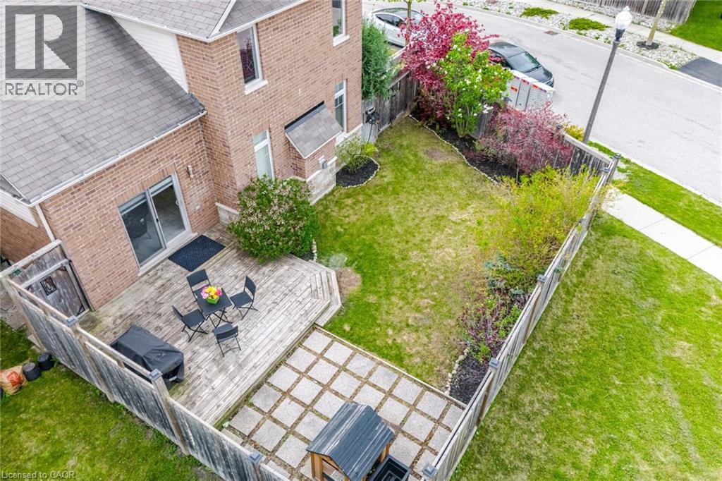 Private backyard featuring a wooden fence, a spacious deck, and a grass lawn with planted shrubs - 58 Doon Creek Street, Kitchener, ON - Outdoor