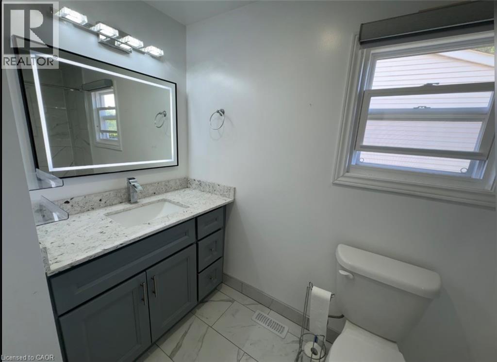 Bathroom vanity featuring gray cabinetry, a light-toned countertop, and an integrated rectangular sink with a chrome faucet - 28 Timberlane Crescent Unit# Upper, Kitchener, ON - Indoor Photo Showing Bathroom