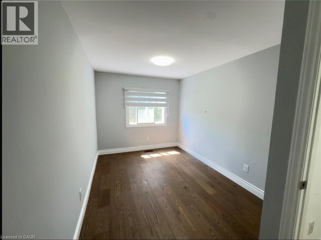 Spacious room featuring wood-finish flooring, light gray wall finishes, a window with horizontal blinds, and a flush-mount ceiling light - 28 Timberlane Crescent Unit# Upper, Kitchener, ON - Indoor Photo Showing Other Room
