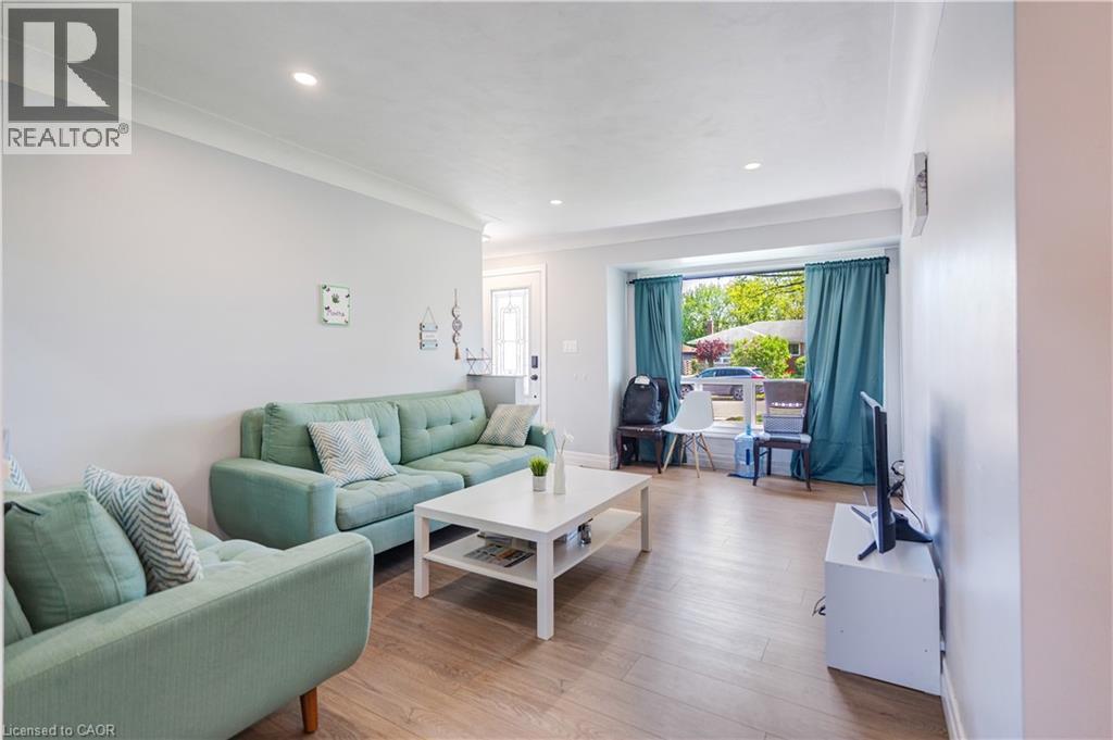 Spacious living area featuring wood-finish flooring, recessed lighting, crown molding, and a prominent bay window - 100 Lauris Avenue, Cambridge, ON - Indoor Photo Showing Living Room