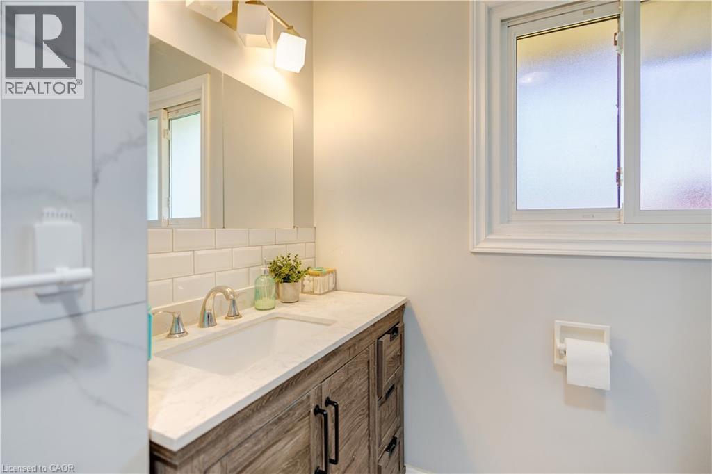 Bathroom vanity with a light wood-finish cabinet, white countertop, and integrated sink - 100 Lauris Avenue, Cambridge, ON - Indoor Photo Showing Bathroom
