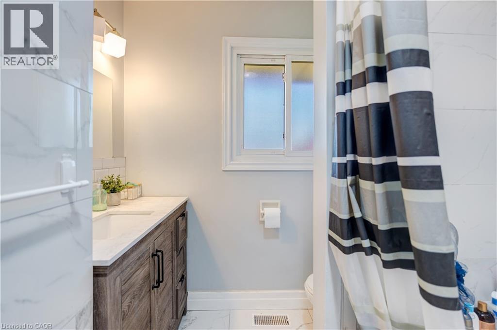 Bathroom featuring a wood-finish vanity with a white countertop and integrated sink - 100 Lauris Avenue, Cambridge, ON - Indoor Photo Showing Bathroom
