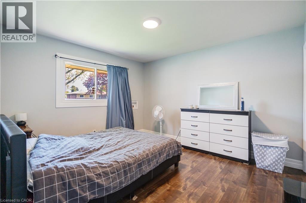 Bedroom featuring wood-finish flooring, a contemporary ceiling light fixture, and light-toned walls - 100 Lauris Avenue, Cambridge, ON - Indoor Photo Showing Bedroom