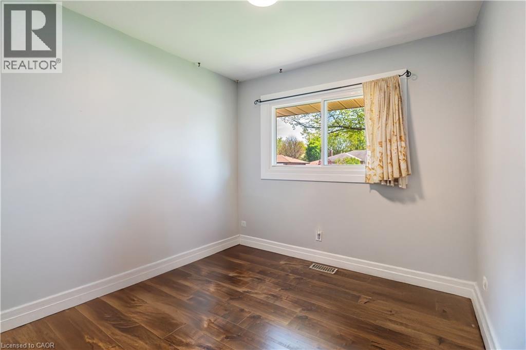 Room featuring wood-finish flooring, light grey painted walls, white baseboards, and a white-framed window - 100 Lauris Avenue, Cambridge, ON - Indoor Photo Showing Other Room