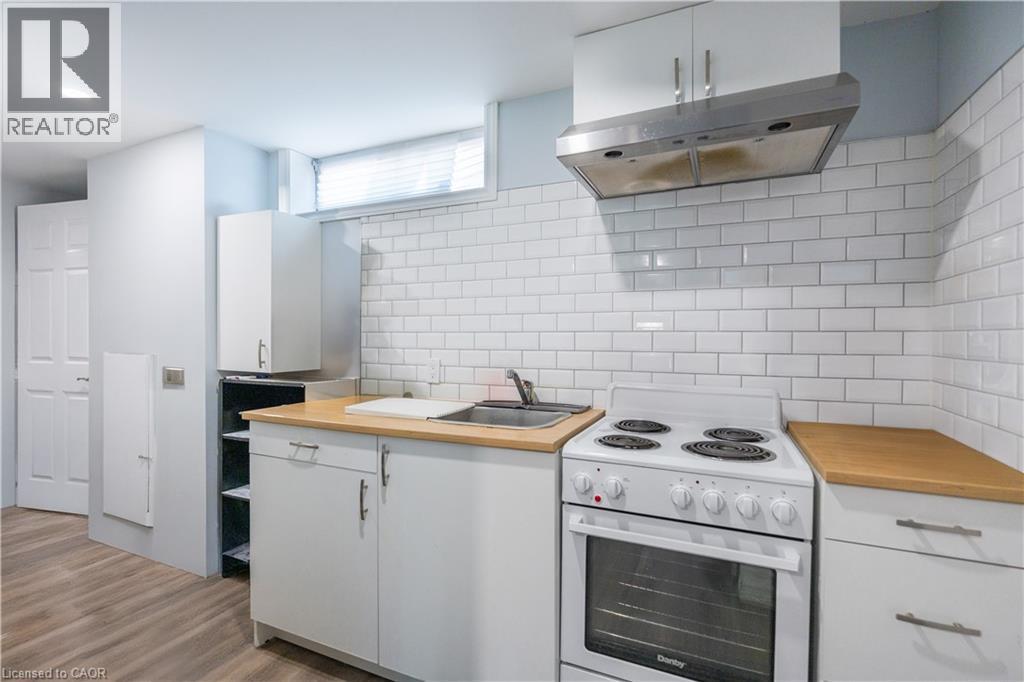 Kitchenette featuring white cabinetry, wood-finish countertops, stainless steel sink, and subway tile backsplash - 100 Lauris Avenue, Cambridge, ON - Indoor Photo Showing Kitchen