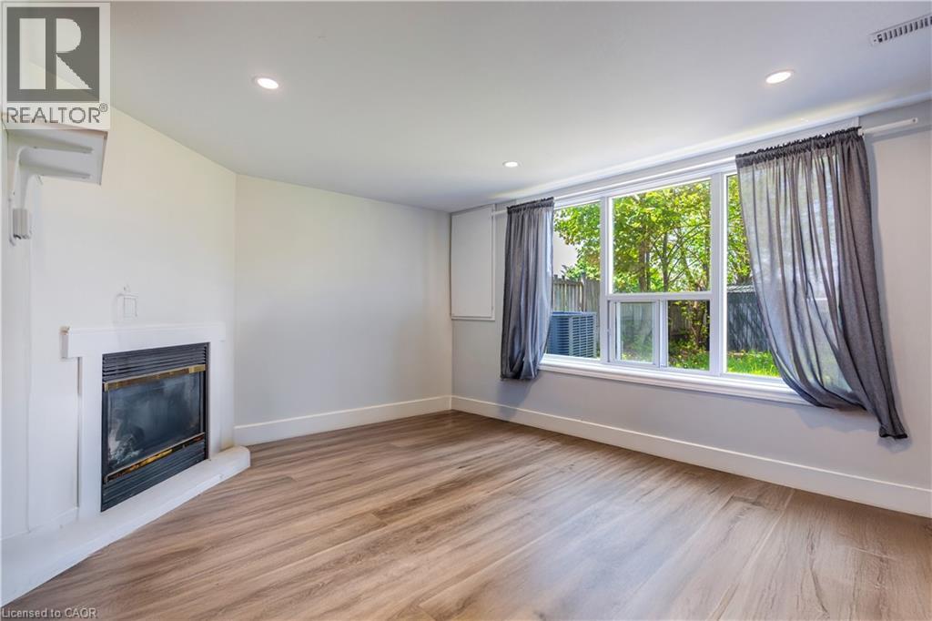 Spacious room featuring wood-finish flooring, a contemporary fireplace, and recessed lighting - 100 Lauris Avenue, Cambridge, ON - Indoor With Fireplace