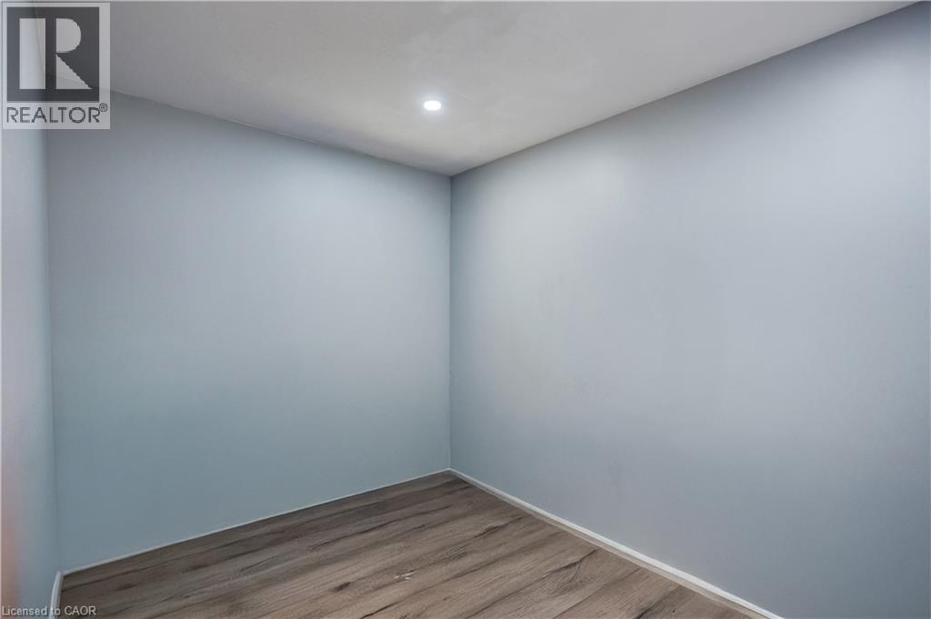 Room featuring light blue walls, recessed ceiling lighting, wood-finish flooring, and white baseboards - 100 Lauris Avenue, Cambridge, ON - Indoor Photo Showing Other Room
