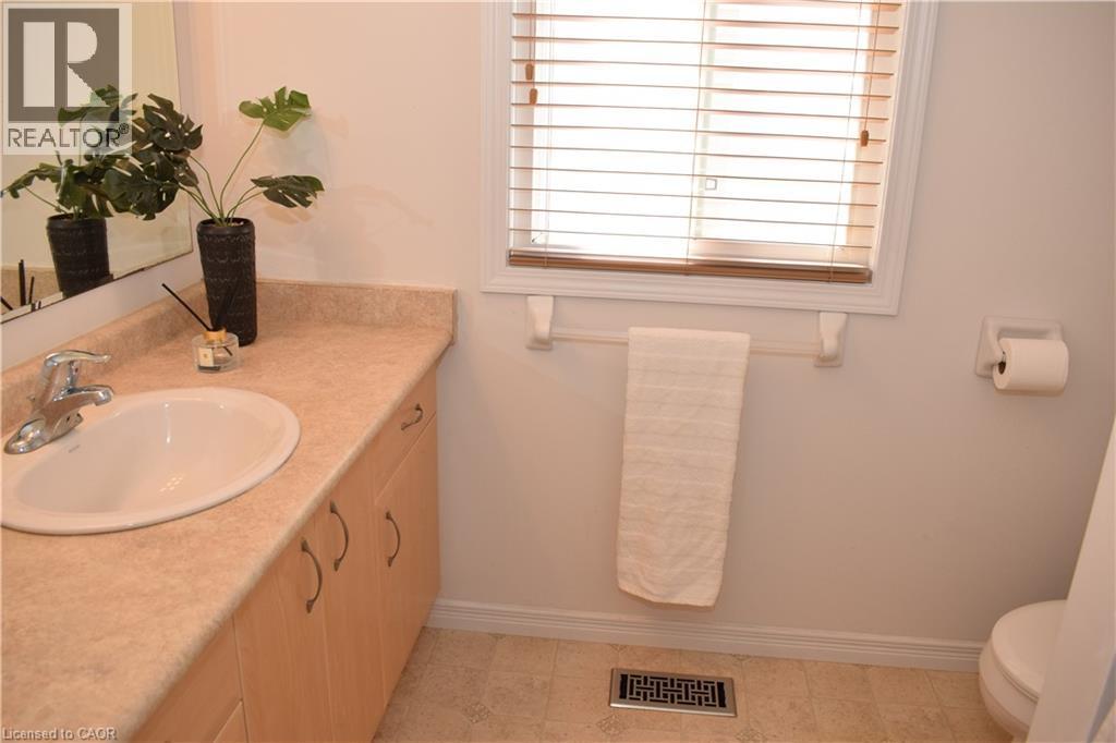 Bathroom featuring a light-toned vanity with an integrated sink, a window with horizontal blinds, a mounted mirror, and light-colored flooring - 28 Lemon Grass Street, Kitchener, ON - Indoor Photo Showing Bathroom