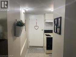Compact kitchen area featuring a gas range, white cabinetry, and a range hood, complemented by tile flooring -