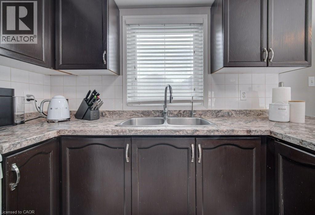 Kitchen with dark wood cabinetry, a double basin stainless steel sink, and a speckled countertop - 334 Christopher Drive, Cambridge, ON - Indoor Photo Showing Kitchen With Double Sink