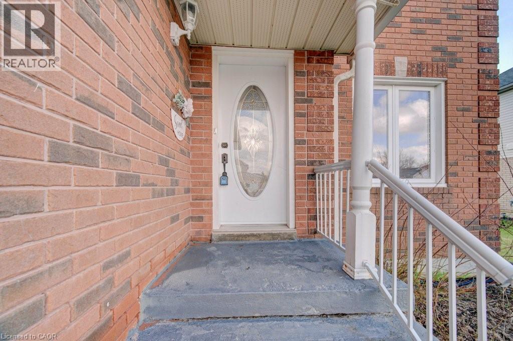 Brick exterior featuring a covered entryway with a white door, an oval glass insert, and a white railing - 334 Christopher Drive, Cambridge, ON - Outdoor With Exterior