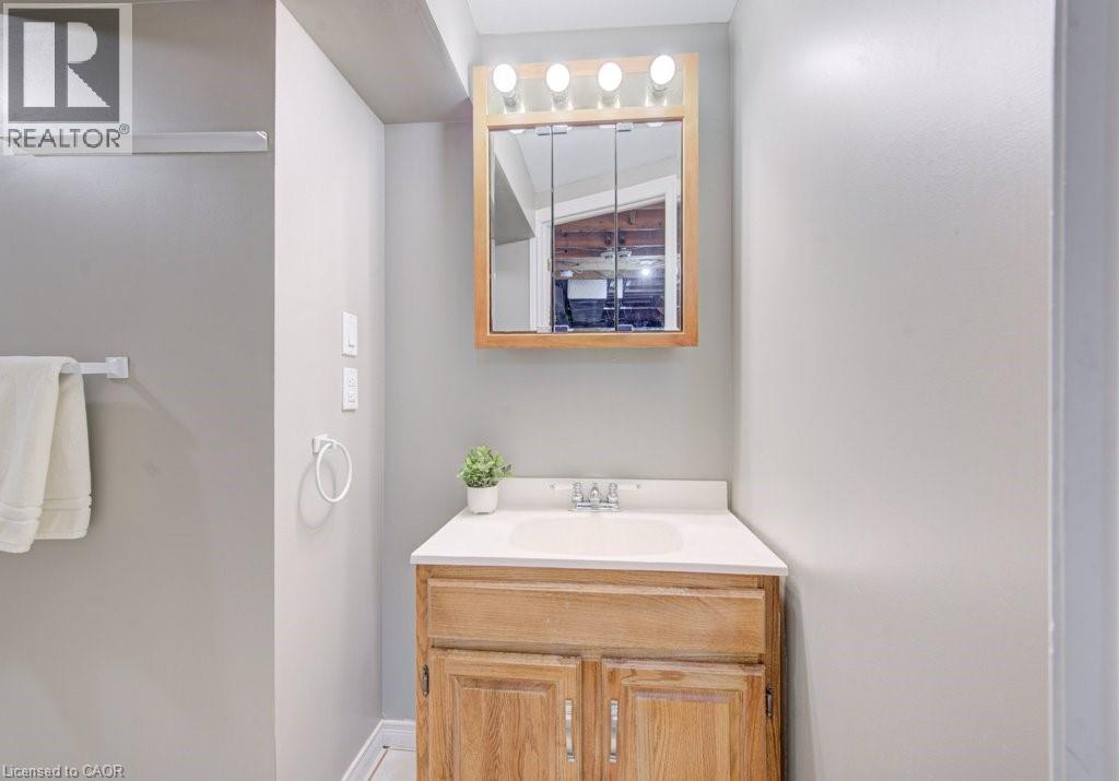 Vanity area featuring a wood-finish cabinet, white countertop with an integrated sink, and a mirrored medicine cabinet with overhead lighting - 334 Christopher Drive, Cambridge, ON - Indoor Photo Showing Bathroom