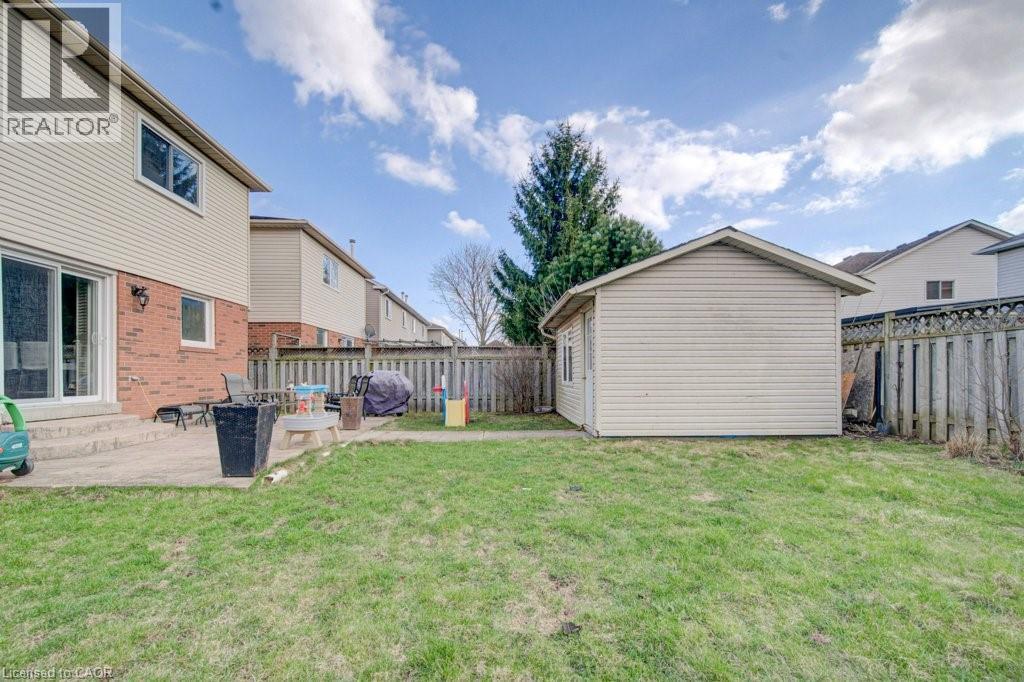 Spacious backyard with a detached storage shed, a concrete patio, and a wooden privacy fence - 334 Christopher Drive, Cambridge, ON - Outdoor With Exterior