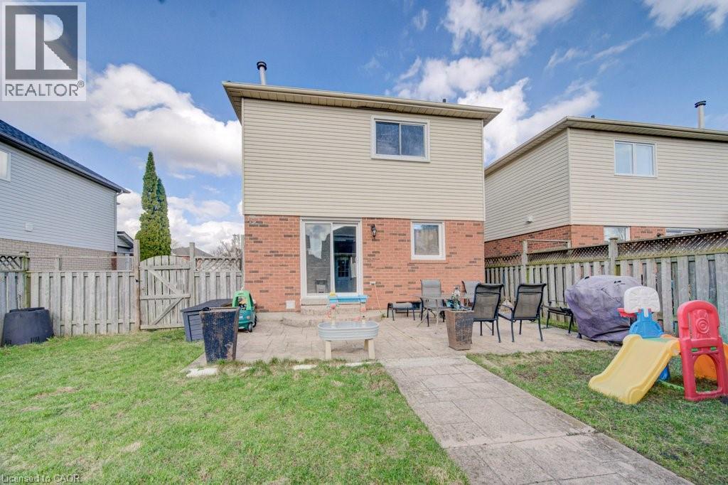 Expansive backyard featuring a concrete patio, a sliding glass door, and a grass lawn - 334 Christopher Drive, Cambridge, ON - Outdoor With Exterior