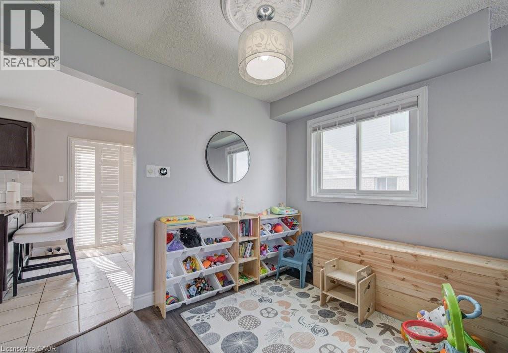 Spacious interior room featuring wood-finish flooring, a contemporary ceiling light fixture with decorative medallion, a large window with white trim, and light gray wall paint - 334 Christopher Drive, Cambridge, ON - Indoor
