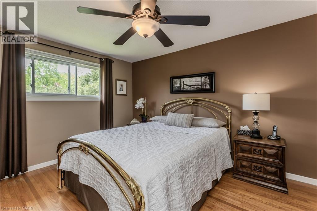 Bedroom featuring wood-finish flooring, a ceiling fan, and a window with exterior tree views - 643 Artreva Crescent, Burlington, ON - Indoor Photo Showing Bedroom