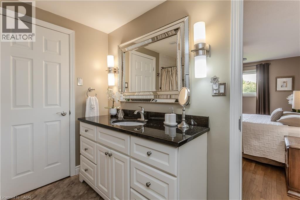 Bathroom vanity featuring white cabinetry, dark countertop, and a vessel sink - 643 Artreva Crescent, Burlington, ON - Indoor