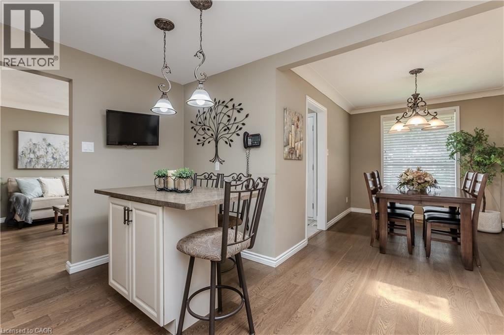 Kitchen peninsula featuring a stone-finish countertop, pendant lighting, and white base cabinetry - 643 Artreva Crescent, Burlington, ON - Indoor Photo Showing Dining Room