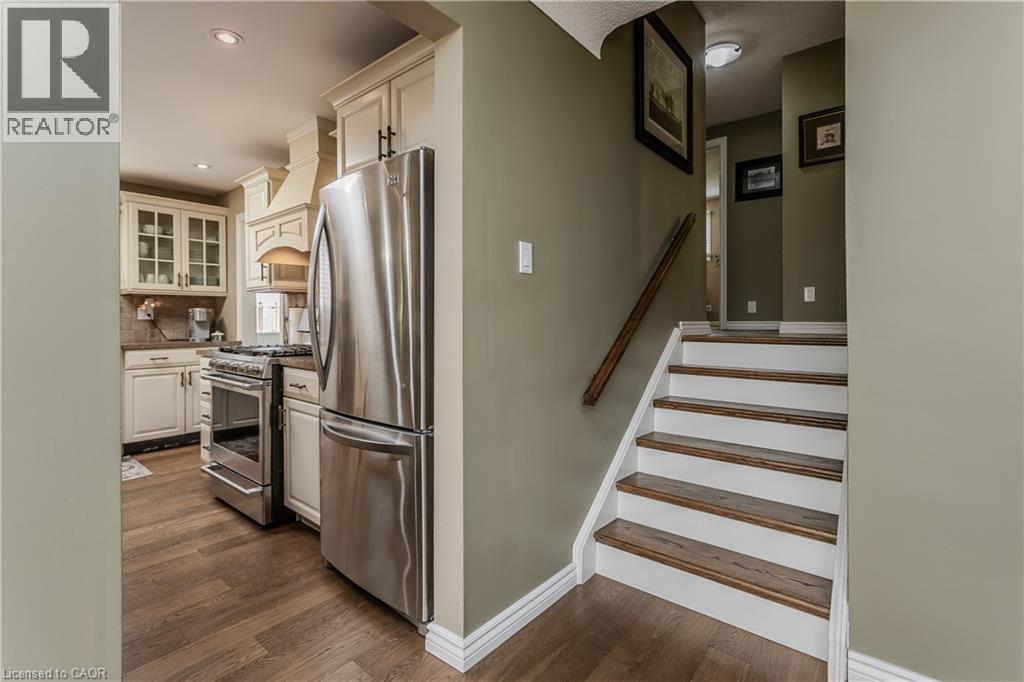 Kitchen with cream cabinetry, stainless steel appliances, and wood-finish flooring - 643 Artreva Crescent, Burlington, ON - Indoor
