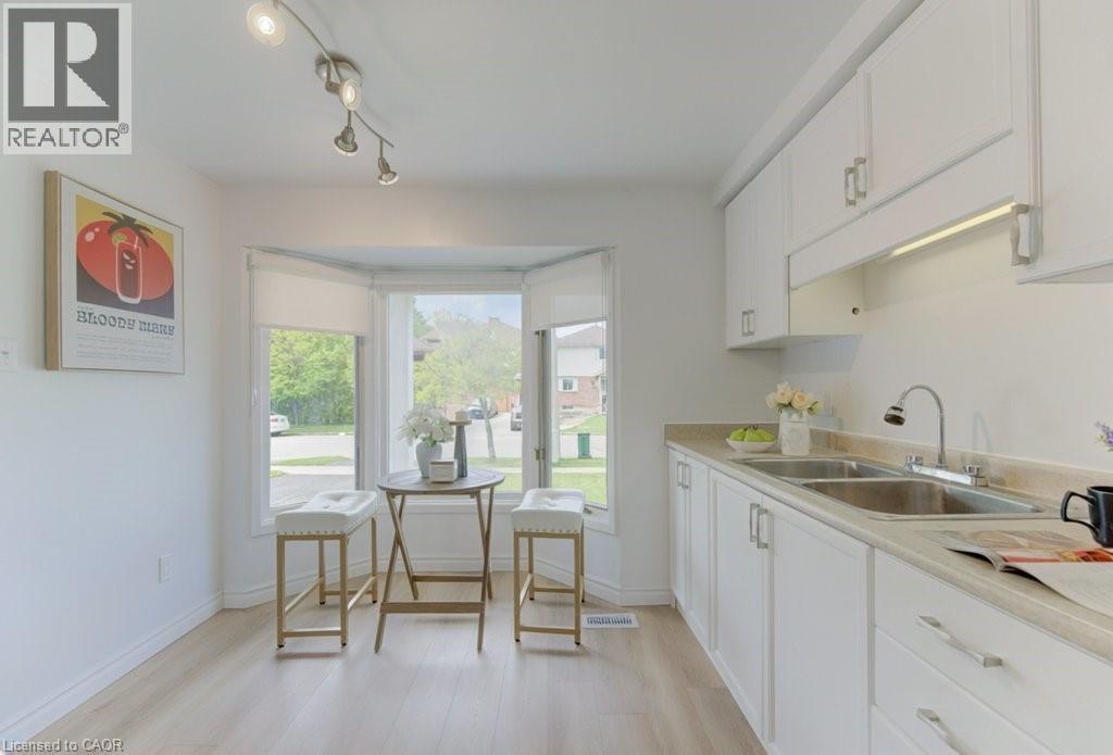 White kitchen featuring abundant cabinetry with silver-tone hardware, a dual stainless steel sink, and light-colored countertops - 603 Pinerow Crescent Unit# B, Waterloo, ON - Indoor Photo Showing Kitchen With Double Sink