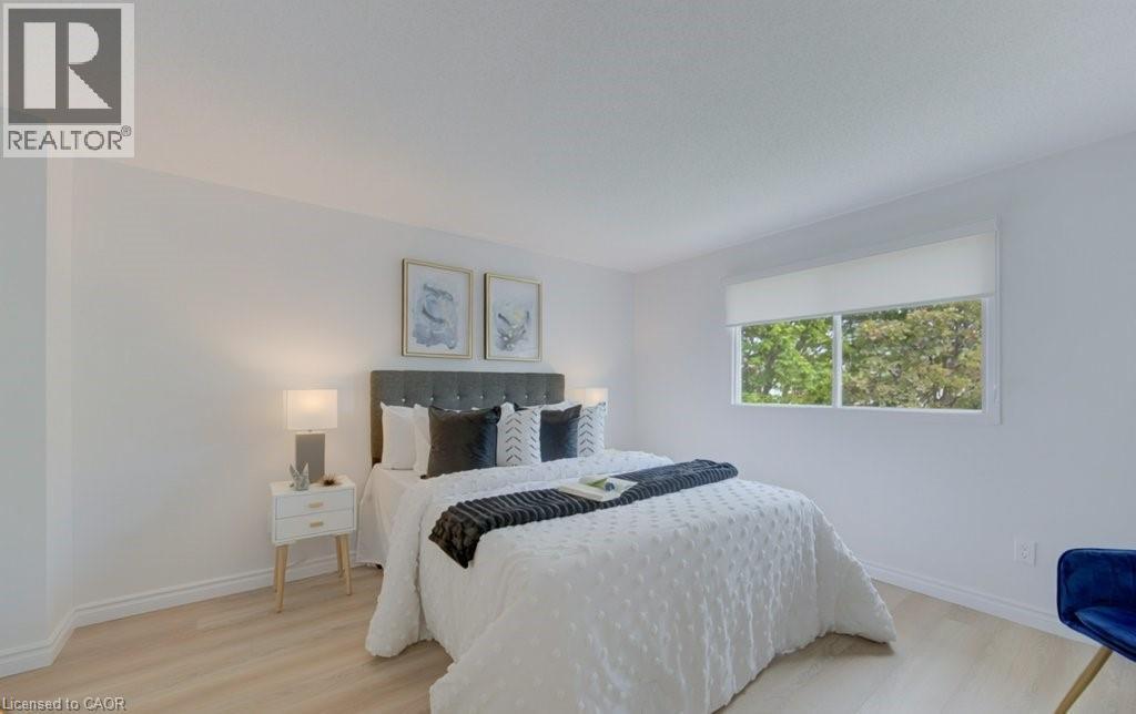 Bright bedroom featuring a large window, light wood-finish flooring, white walls, and white baseboards - 603 Pinerow Crescent Unit# B, Waterloo, ON - Indoor Photo Showing Bedroom