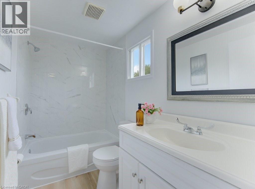 Bathroom featuring a white vanity with integrated sink, chrome fixtures, and a framed mirror - 603 Pinerow Crescent Unit# B, Waterloo, ON - Indoor Photo Showing Bathroom