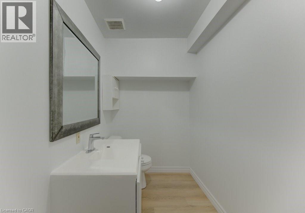 Contemporary powder room featuring a white vanity with integrated sink, chrome faucet, and a large framed mirror - 603 Pinerow Crescent Unit# B, Waterloo, ON - Indoor