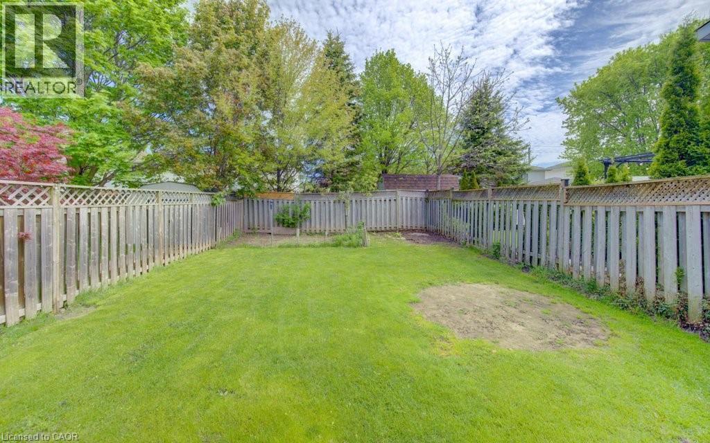 Spacious backyard featuring a lush green lawn, full perimeter privacy fencing, and mature surrounding trees - 603 Pinerow Crescent Unit# B, Waterloo, ON - Outdoor