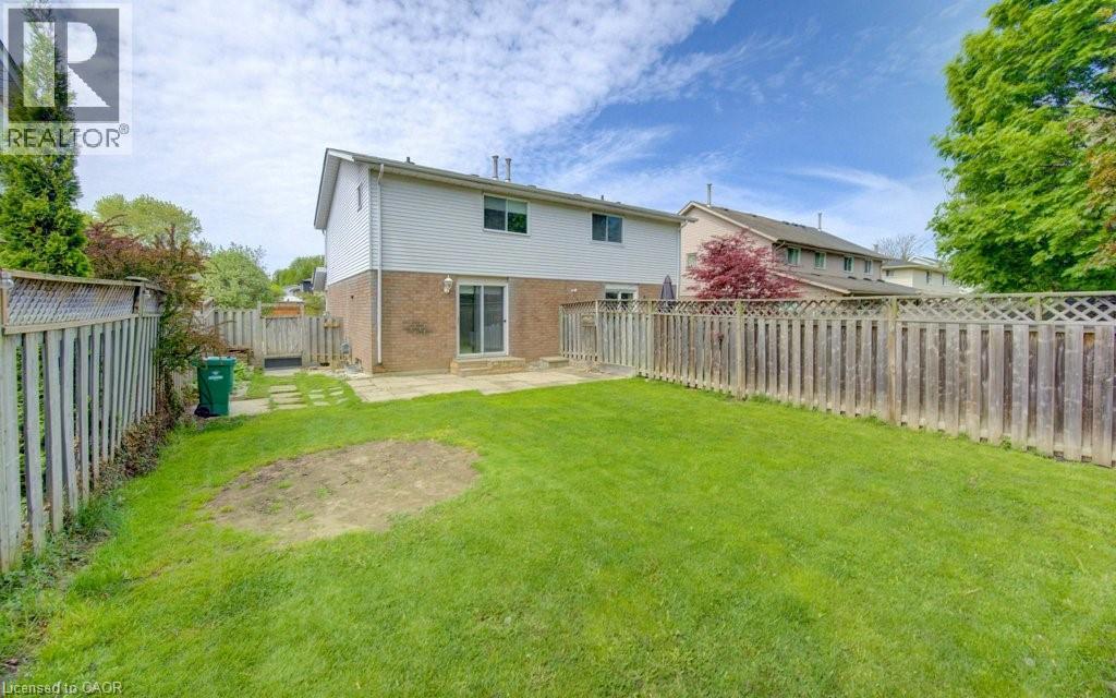 Spacious backyard featuring a large grass lawn, perimeter fencing, and a patio area - 603 Pinerow Crescent Unit# B, Waterloo, ON - Outdoor With Backyard