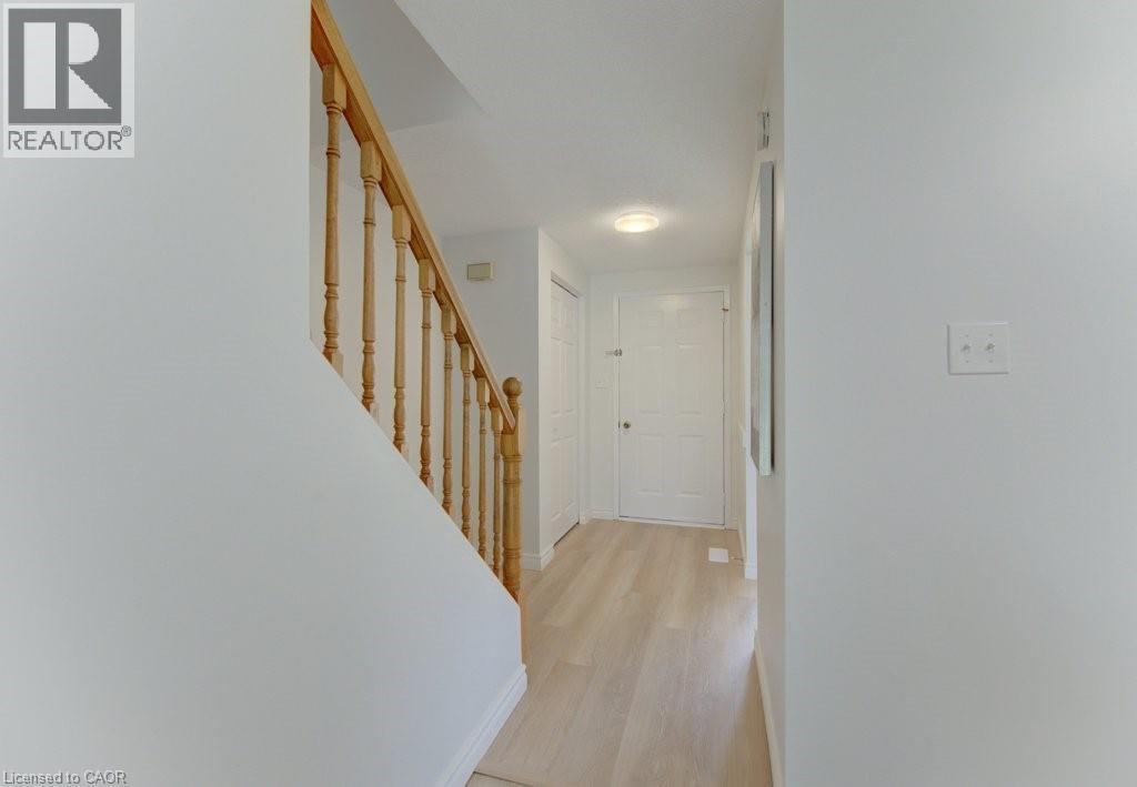 Hallway featuring wood-finish flooring, white walls, a staircase with wood balusters and handrail, and a flush-mount ceiling light - 603 Pinerow Crescent Unit# B, Waterloo, ON - Indoor Photo Showing Other Room