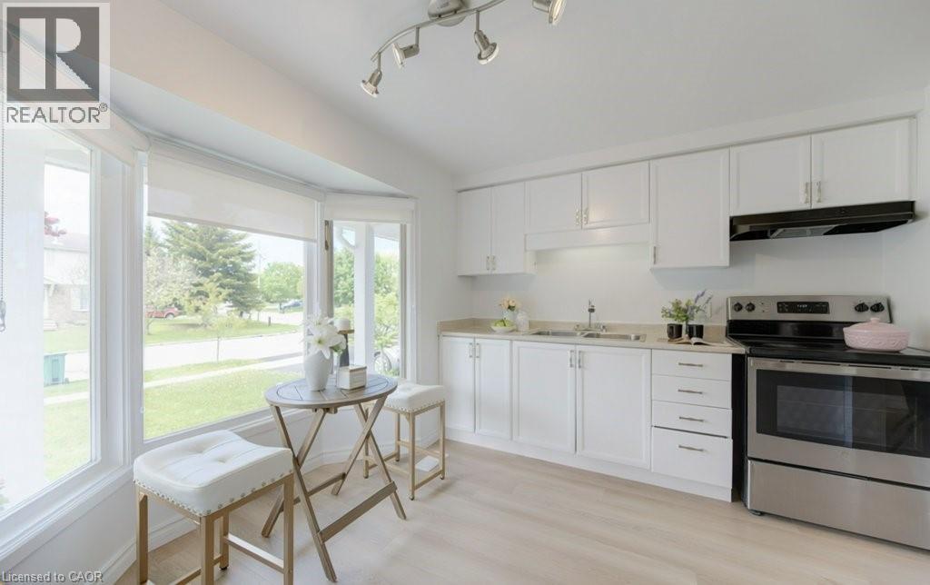 Bright kitchen space featuring white cabinetry, light countertops, wood-finish flooring, and stainless steel appliances - 603 Pinerow Crescent Unit# B, Waterloo, ON - Indoor Photo Showing Kitchen With Stainless Steel Kitchen With Double Sink