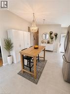 Expansive kitchen area featuring large format tile flooring, a chandelier light fixture, and a built-in white cabinetry wall -