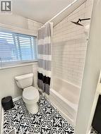 Bathroom featuring a combination tub and shower with white subway tile surround, matte black rainfall showerhead, and a patterned floor tile -