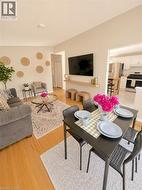 Open-concept living and dining area featuring wood-finish flooring, neutral wall tones, and a recessed ceiling light -