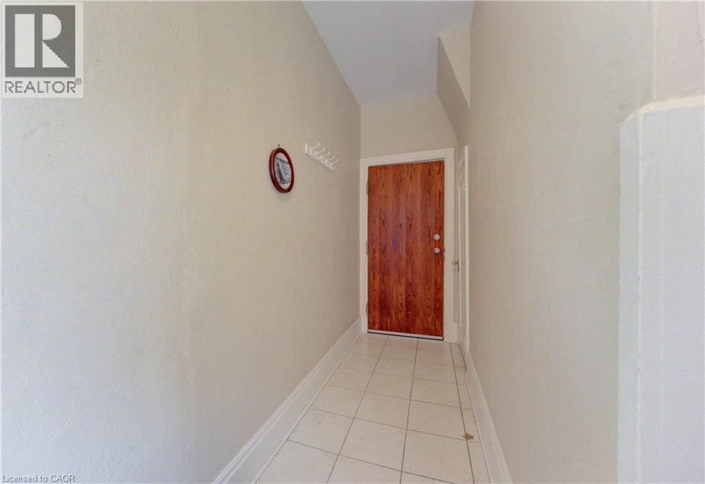 Front entry access to main floor unit and lower level shared laundry and utility space. Featuring a wood-finish door, light-toned walls, and easy care tile flooring. - 48 Breithaupt Street, Kitchener, ON - Indoor Photo Showing Other Room