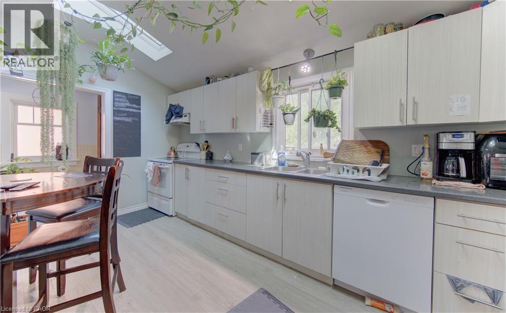 Functional kitchen featuring light-toned cabinetry, a skylight, a double-basin sink, and a built-in dishwasher - 48 Breithaupt Street, Kitchener, ON - Indoor