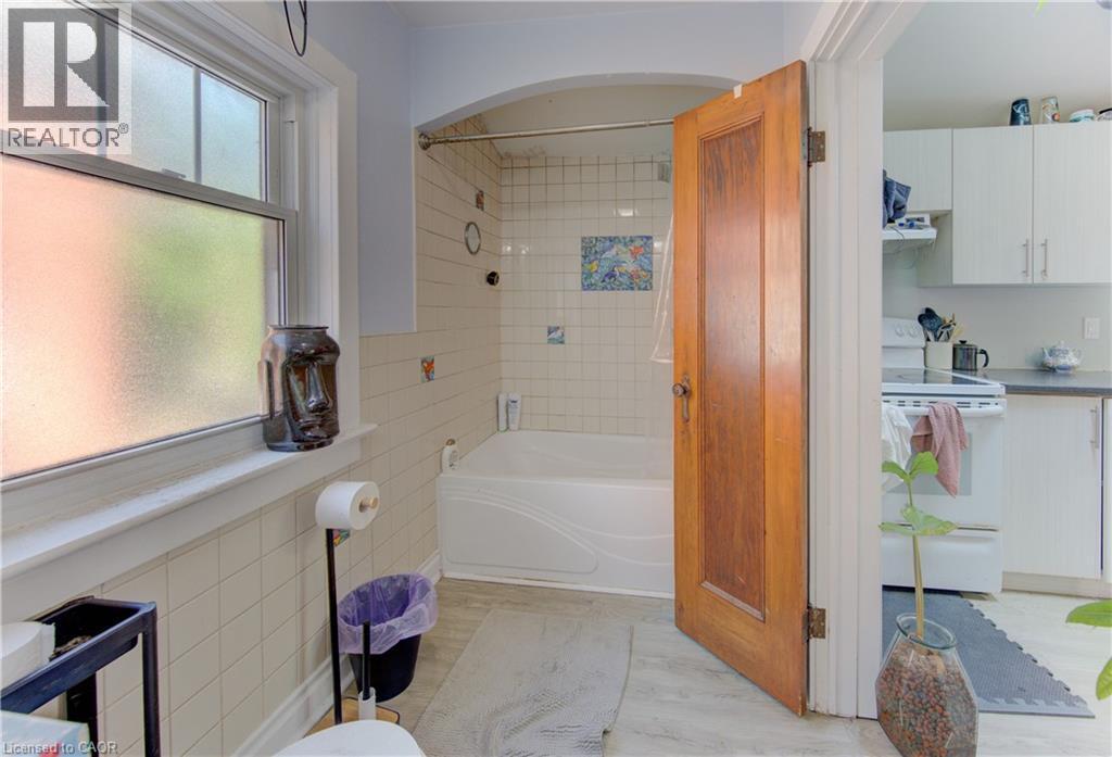 Main floor bathroom featuring a tiled shower/tub combination, frosted window, and wood-finish door - 48 Breithaupt Street, Kitchener, ON - Indoor Photo Showing Bathroom