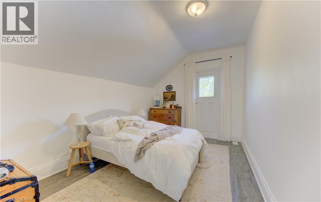Upper bedroom with angled ceiling, white walls, and access to outdoor porch sitting area - 48 Breithaupt Street, Kitchener, ON - Indoor Photo Showing Bedroom