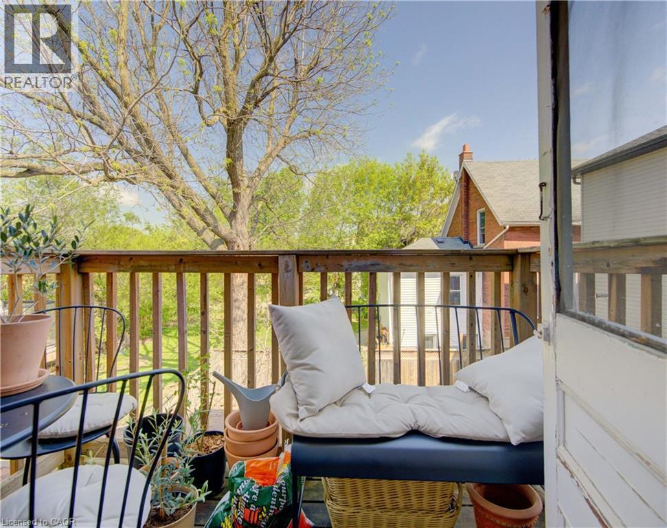 Upper unit outdoor porch sitting area featuring a wood railing and wood-finish flooring - 48 Breithaupt Street, Kitchener, ON -